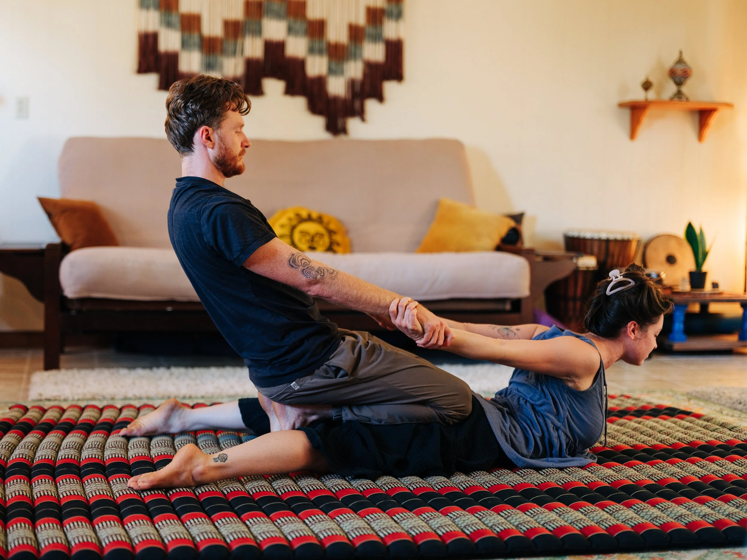 Thai stretch with client lying on floor mat