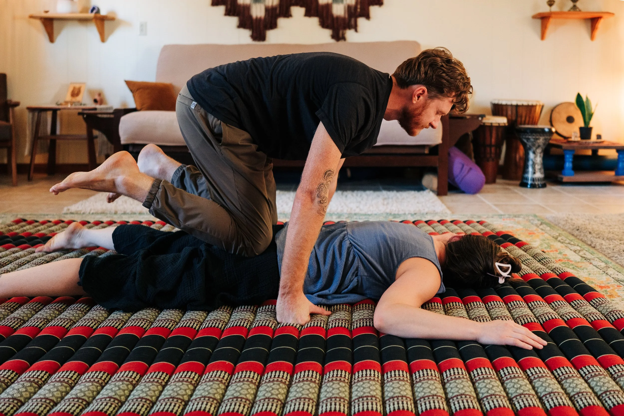Traditional Thai massage knee press on floor mat at Asheville bodywork studio
